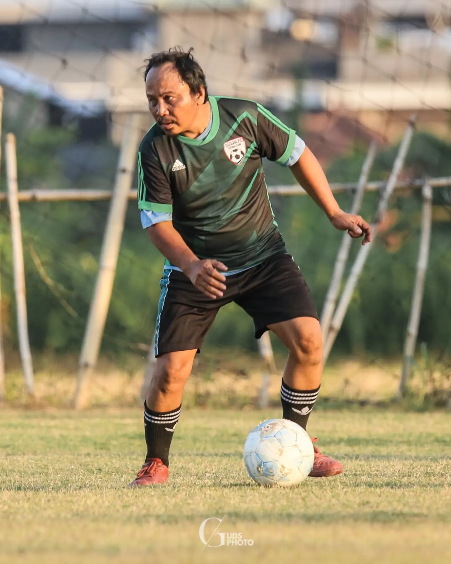 Pemain berjersey hijau mengontrol bola
